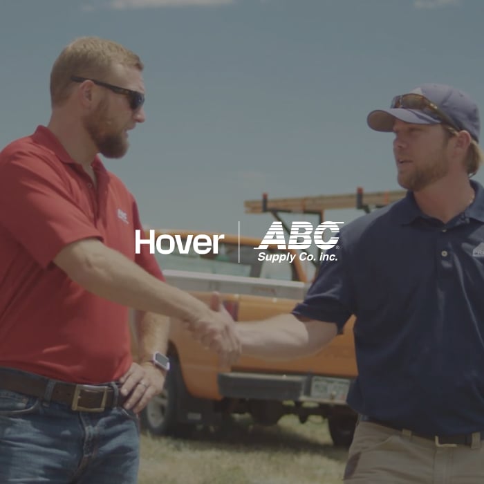 The logos for Hover and ABC Supply. Co superimposed over an image of two men shaking hands.