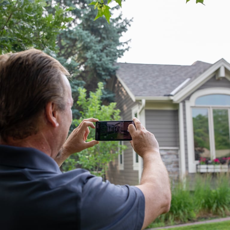 A man using a mobile phone to photograph the exterior of a home